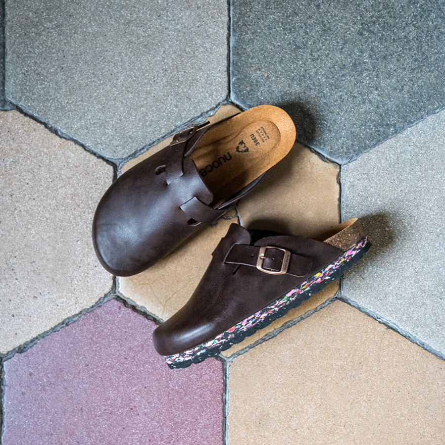 Pair of brown shoes with buckles on a hexagonal tiled floor.